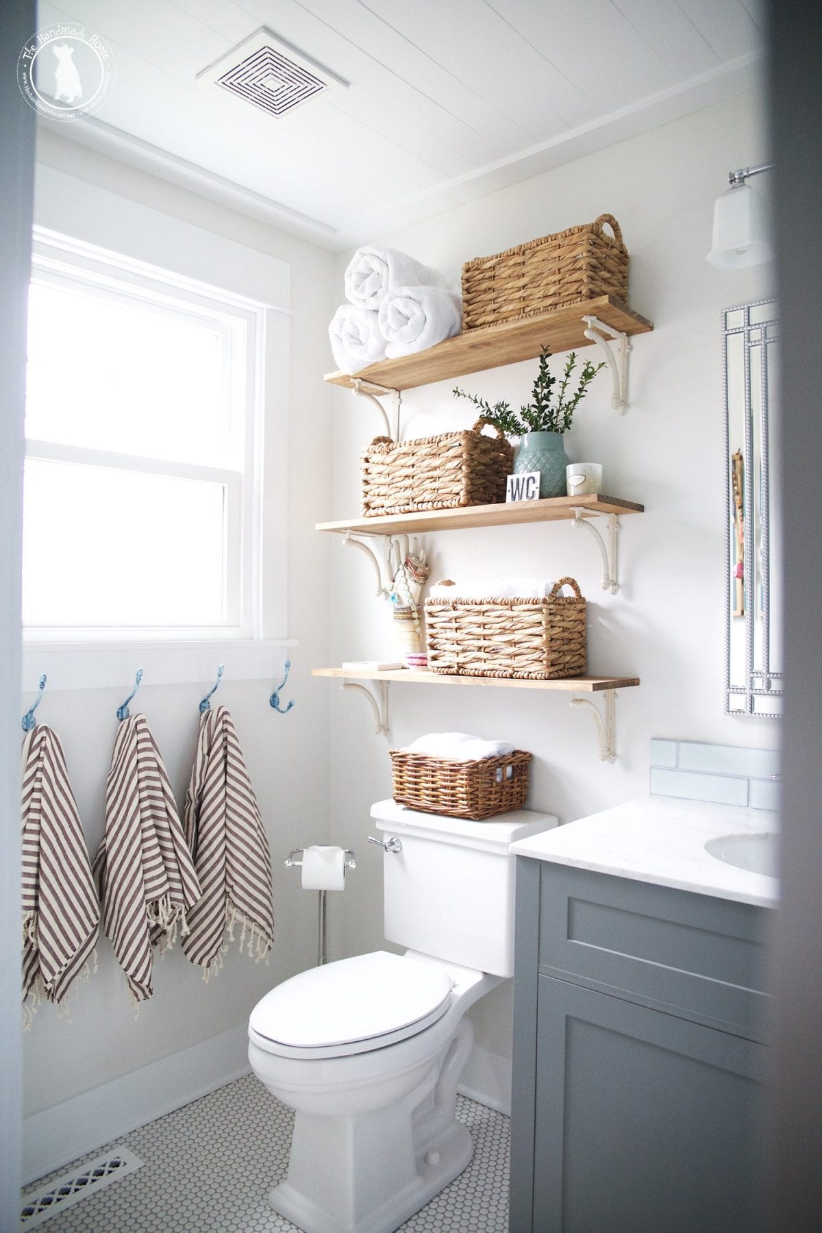 Neat bathroom organized with shelves, baskets and hooks for towels.